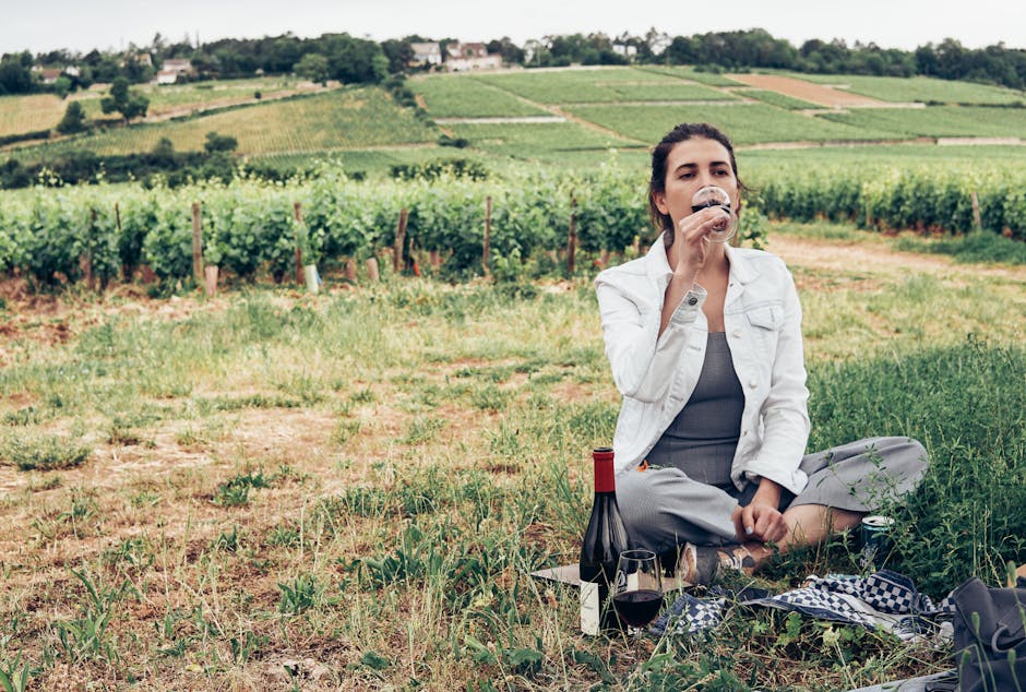 A woman savoring wine in a picturesque vineyard in Bourgogne-Franche-Comté, France.